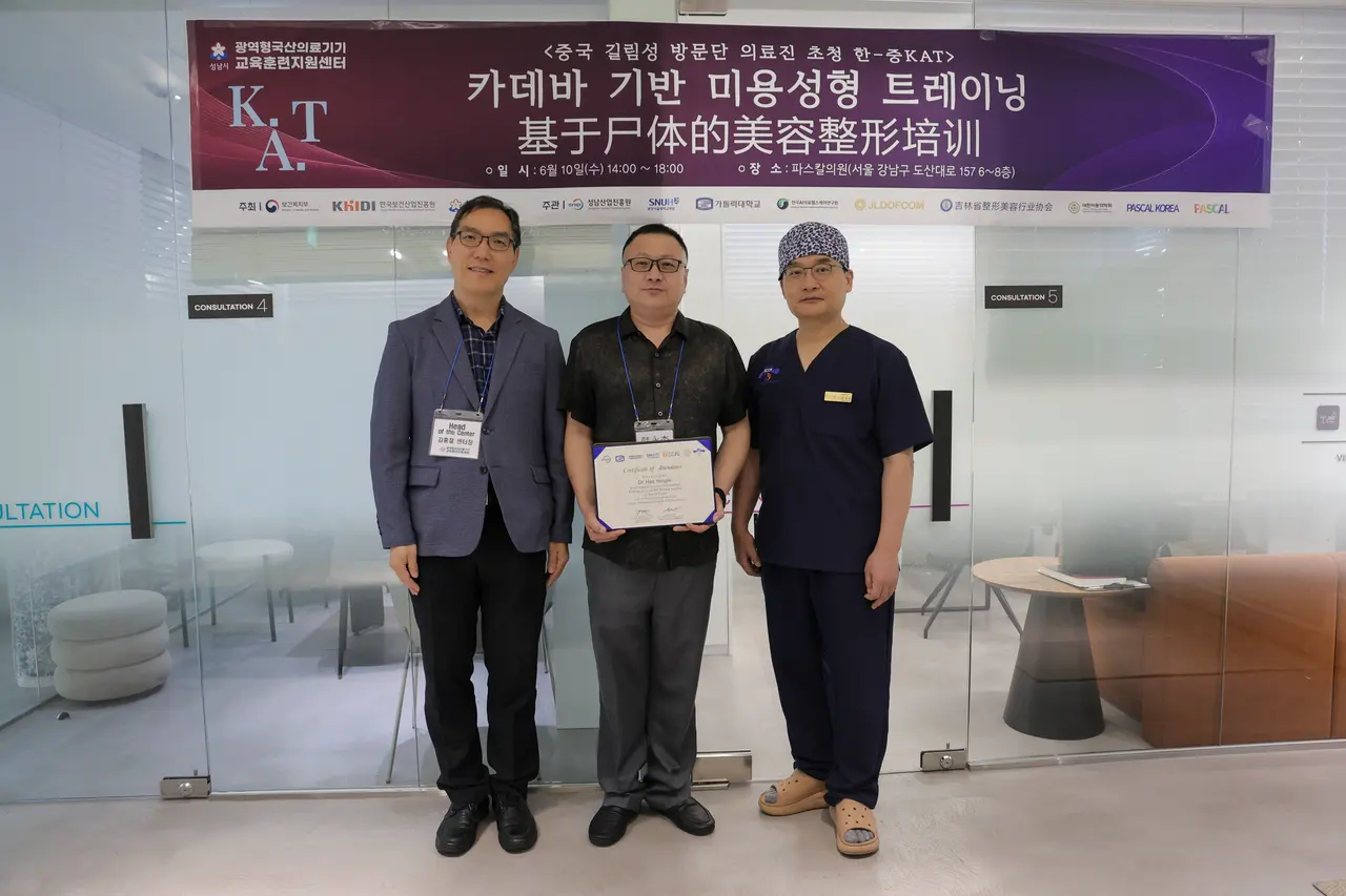 A visiting doctor receiving a training certificate in front of the cadaver training banner